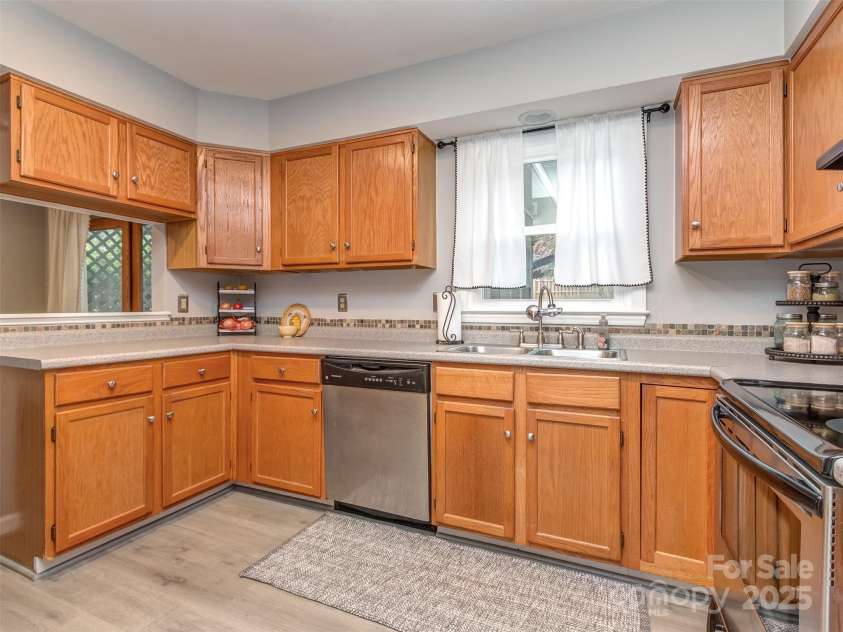 8715 Parkchester Drive, Charlotte, NC 28277.  MLS# CAR4288901, YatesRealty ID 33815. Kitchen has mosaic tile backsplash, laminate wood flooring, stainless appliances, pantry & is open to the breakfast area & dining room.