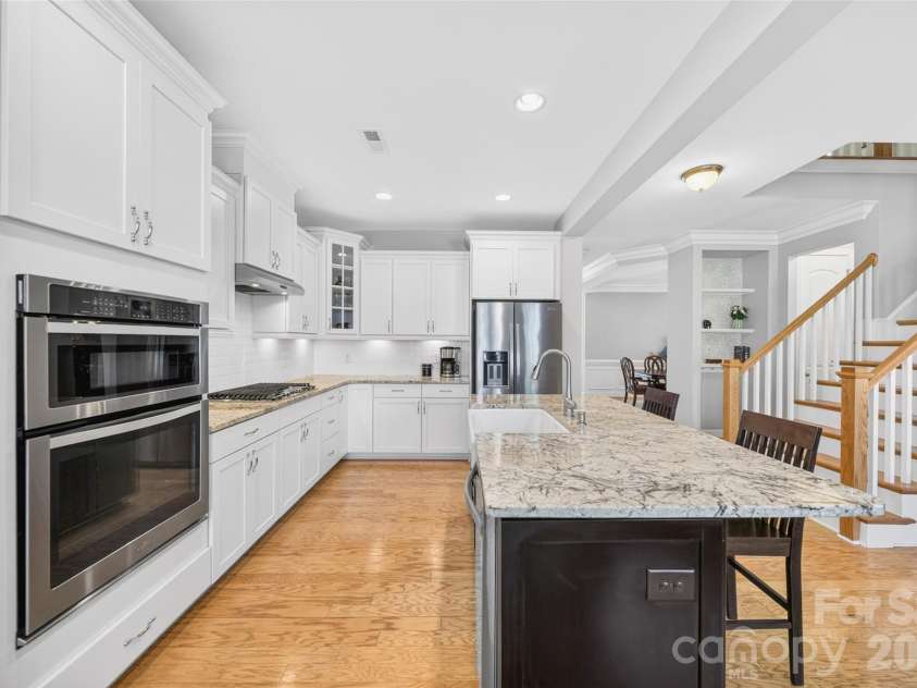 103 Cranbrook Lane, Mooresville, NC 28117.  MLS# CAR4392478, YatesRealty ID 33887. Gourmet kitchen featuring granite countertops, farmhouse-style sink, and gas cooktop with open floor plan.