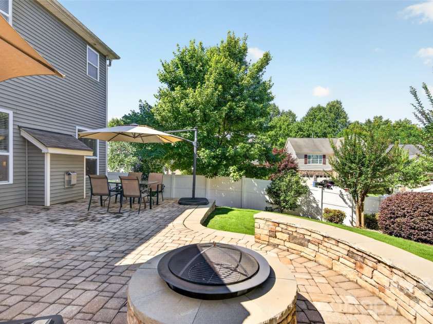 103 Cranbrook Lane, Mooresville, NC 28117.  MLS# CAR4392478, YatesRealty ID 33887. Hardscaped back patio featuring a built-in fire pit with surrounding seating wall and outdoor lighting.