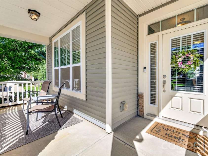 103 Cranbrook Lane, Mooresville, NC 28117.  MLS# CAR4392478, YatesRealty ID 33887. Inviting covered front porch featuring rocking chairs, decorative columns, and white picket railings.