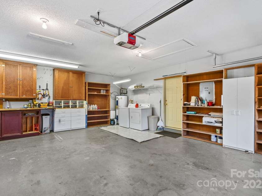 27 Eden Glen Road, Black Mountain, NC 28711.  MLS# CAR4292054, YatesRealty ID 33978. This oversized garage is a dream for hobbyists and DIY enthusiasts, offering abundant built-in storage, workbenches, and shelving to keep everything organized. The space also features a washer and dryer area and ple