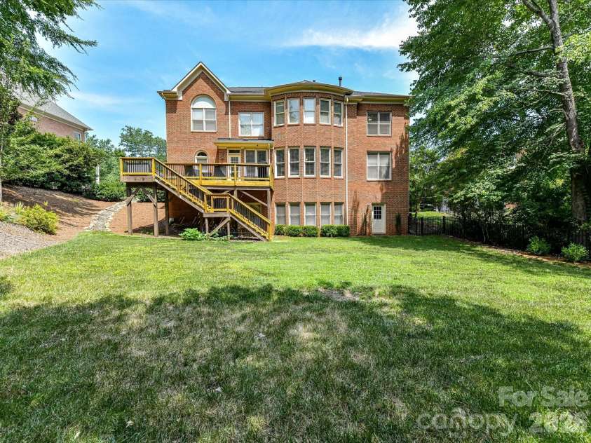 515 Three Greens Drive, Huntersville, NC 28078.  MLS# CAR4397315, YatesRealty ID 34047. Expansive, private backyard features a spacious elevated deck overlooking a lush lawn, mature trees, and a full-brick exterior designed for relaxing and entertaining.