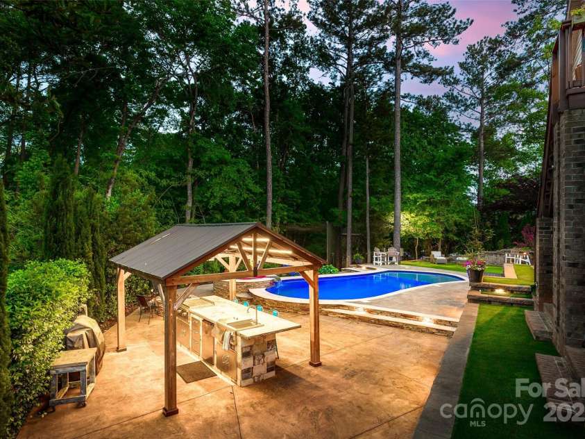 288 Ridge Reserve Drive, Lake Wylie, SC 29710.  MLS# CAR4249323, YatesRealty ID 34210. Dine al fresco under the stars with a fully equipped outdoor kitchen, poolside ambiance, and peaceful wooded backdrop.