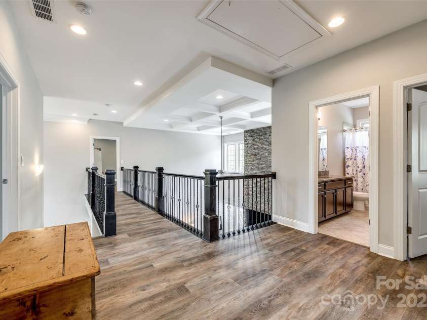288 Ridge Reserve Drive, Lake Wylie, SC 29710.  MLS# CAR4249323, YatesRealty ID 34210. The upper hallway offers a dramatic view of the great room below, accented by coffered ceilings and wrought iron railings—elegance in every detail.