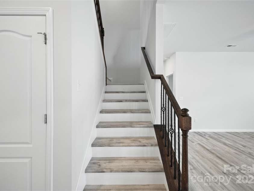 15119 Oleander Drive, Charlotte, NC 28278.  MLS# CAR4272288, YatesRealty ID 34225. Staircase featuring upgraded iron balusters, stained handrail, and matching LVP treads that flow seamlessly from the main level.