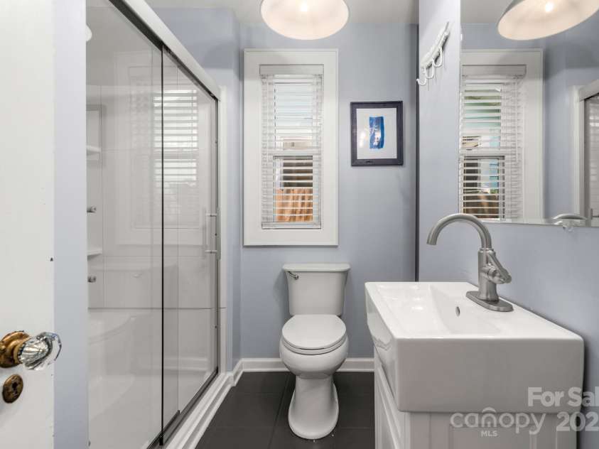 77 Mitchell Avenue, Asheville, NC 28806.  MLS# CAR4285971, YatesRealty ID 34450. Hall bathroom with walk-in shower and built-in, recessed shelving and storage to the left of the vanity.