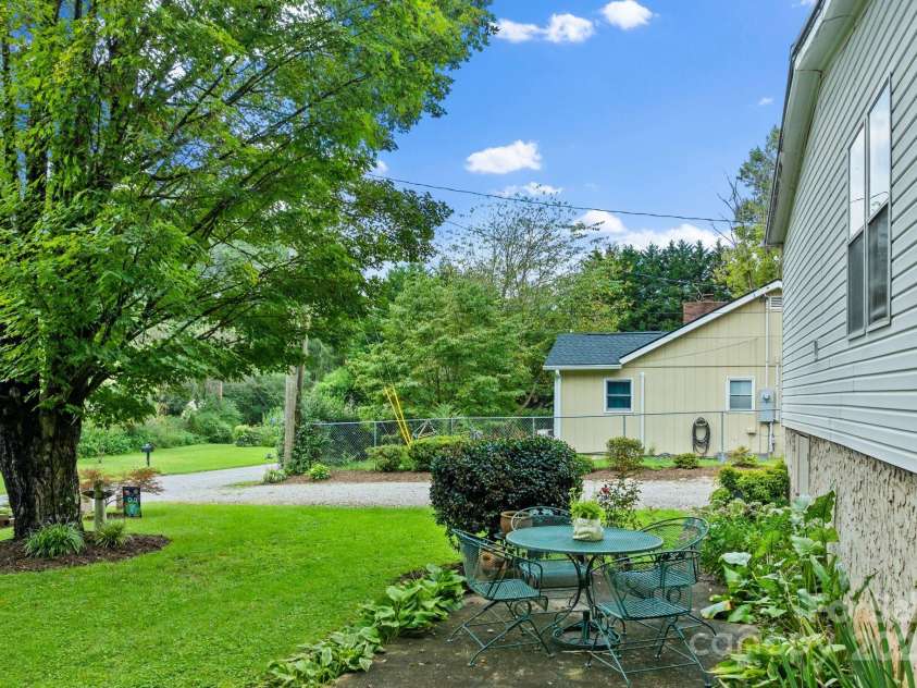 213 Old State Ten Road, Black Mountain, NC 28711.  MLS# CAR4294666, YatesRealty ID 34482. A charming patio area shaded by mature trees, creating the perfect spot for outdoor dining or quiet relaxation.
