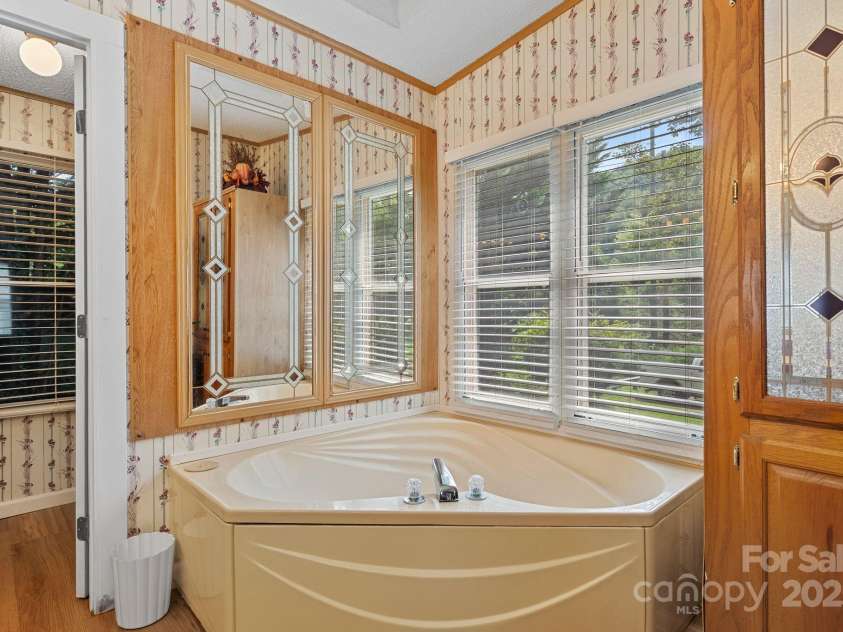 213 Old State Ten Road, Black Mountain, NC 28711.  MLS# CAR4294666, YatesRealty ID 34482. A large garden tub sits beneath bright windows, creating a relaxing retreat with plenty of natural light. With its functional layout and private access from the primary bedroom, this bathroom is designed for ev