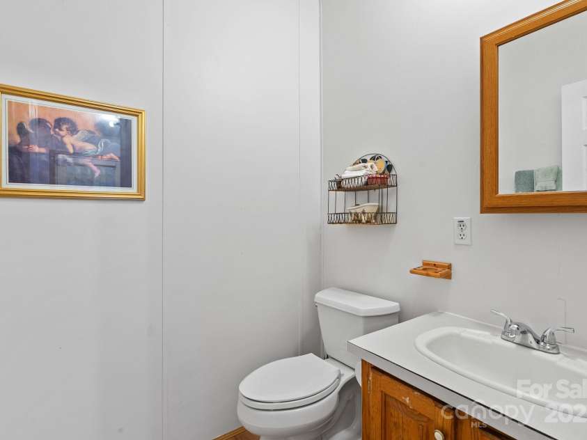 213 Old State Ten Road, Black Mountain, NC 28711.  MLS# CAR4294666, YatesRealty ID 34482. Conveniently located just off the laundry room and kitchen, this half bath adds everyday practicality and is perfect for guests. With a sink, mirror, and storage, it’s a functional space that enhances the home’