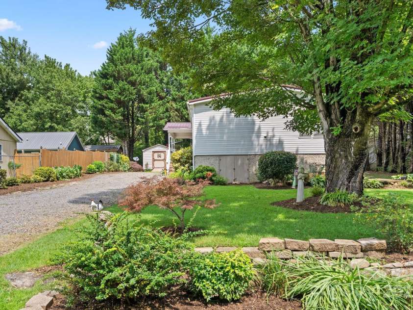 213 Old State Ten Road, Black Mountain, NC 28711.  MLS# CAR4294666, YatesRealty ID 34482. The home is surrounded by mature trees and landscaped beds that create a peaceful, park-like setting. A long gravel driveway offers ample parking and leads to both the welcoming front porch and a storage shed, 