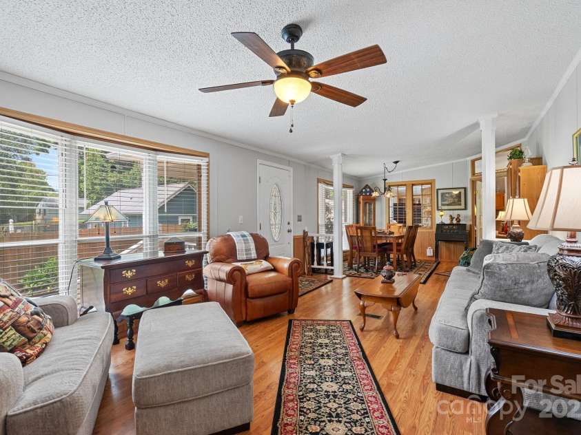 213 Old State Ten Road, Black Mountain, NC 28711.  MLS# CAR4294666, YatesRealty ID 34482. The spacious living room is filled with warmth and natural light, thanks to the beautiful bay windows that frame the space. The open layout flows seamlessly into the dining  and kitchen areas. It's perfect for 