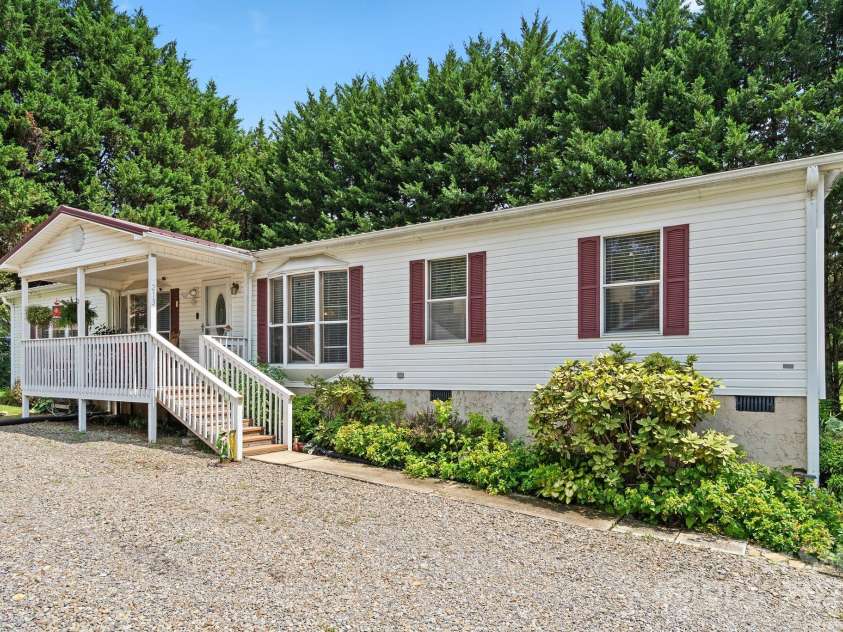 213 Old State Ten Road, Black Mountain, NC 28711.  MLS# CAR4294666, YatesRealty ID 34482. Welcome home to this charming double-wide nestled in a peaceful Black Mountain setting. With its welcoming front porch, fresh landscaping, and mature trees framing the property, this home immediately feels warm