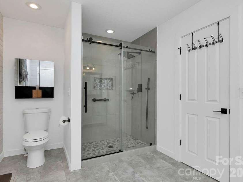 3125 Connestee Trail, Brevard, NC 28712.  MLS# CAR4396358, YatesRealty ID 34599. Primary bath boasts a walk-in shower with custom tile & seamless glass door