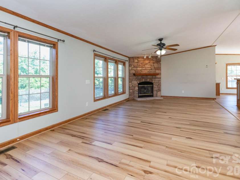71 Teachers Lane, Canton, NC 28716.  MLS# CAR4394186, YatesRealty ID 34734. Bright and open living room featuring updated flooring, oversized windows, and a stunning floor-to-ceiling stone fireplace.