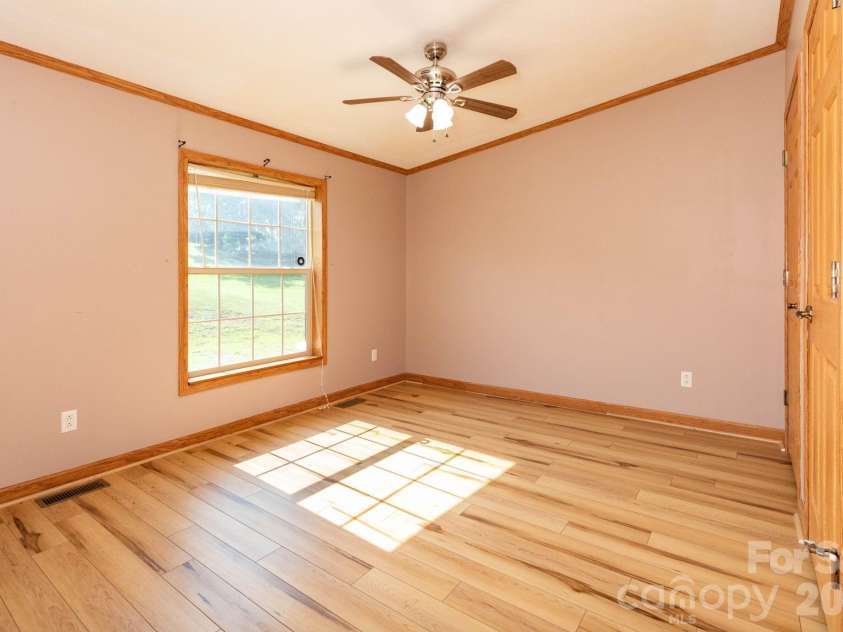 71 Teachers Lane, Canton, NC 28716.  MLS# CAR4394186, YatesRealty ID 34734. Generously sized secondary bedroom with updated flooring, ceiling fan, and large window for natural light.