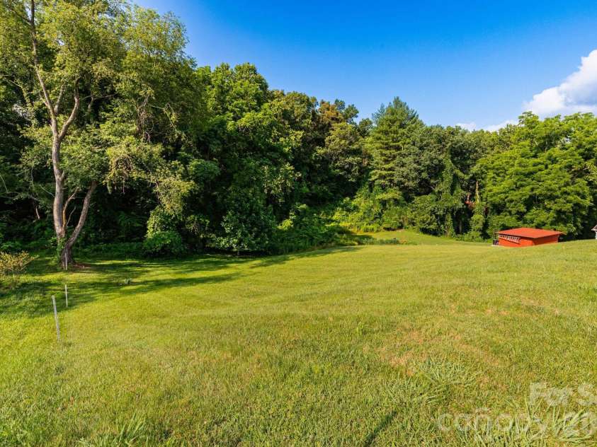 71 Teachers Lane, Canton, NC 28716.  MLS# CAR4394186, YatesRealty ID 34734. Private backyard with a gently sloping lawn bordered by mature trees, providing both space and privacy.