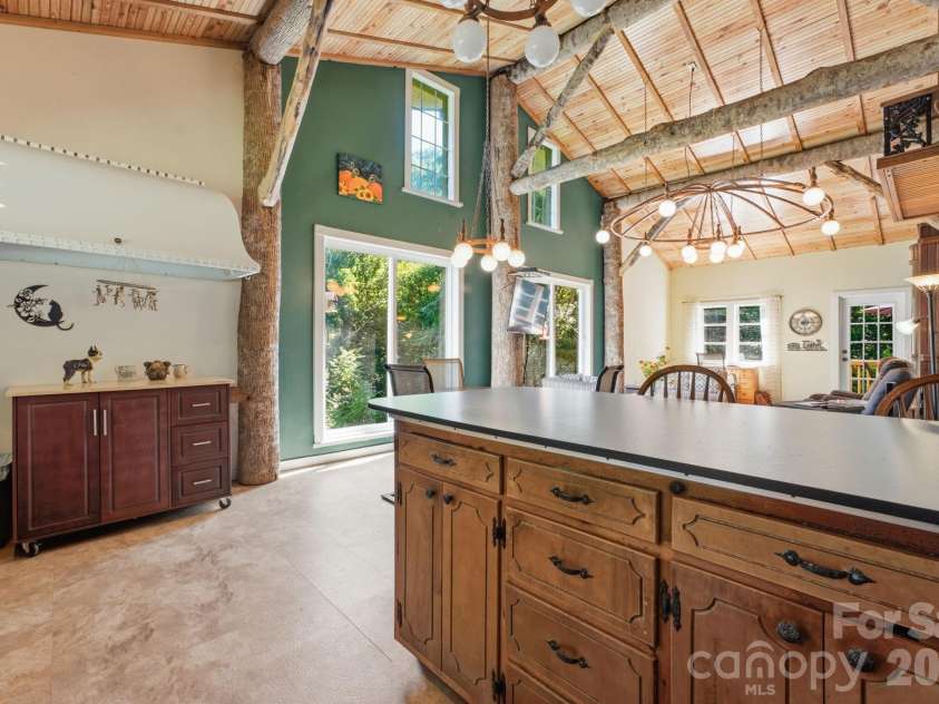 583 Dark Ridge Road, Sylva, NC 28779.  MLS# CAR4394353, YatesRealty ID 34785. Large, raw tree-trunk beams stretch across the vaulted ceiling, showcasing the home’s rustic artistry.