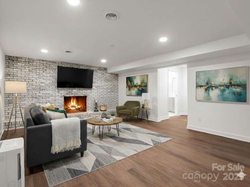 30 Patti Drive, Fletcher, NC 28732.  MLS# CAR4296193, YatesRealty ID 34869. Second view of large + versatile bonus room in basement with statement wood burning fireplace. (Virtually Staged)