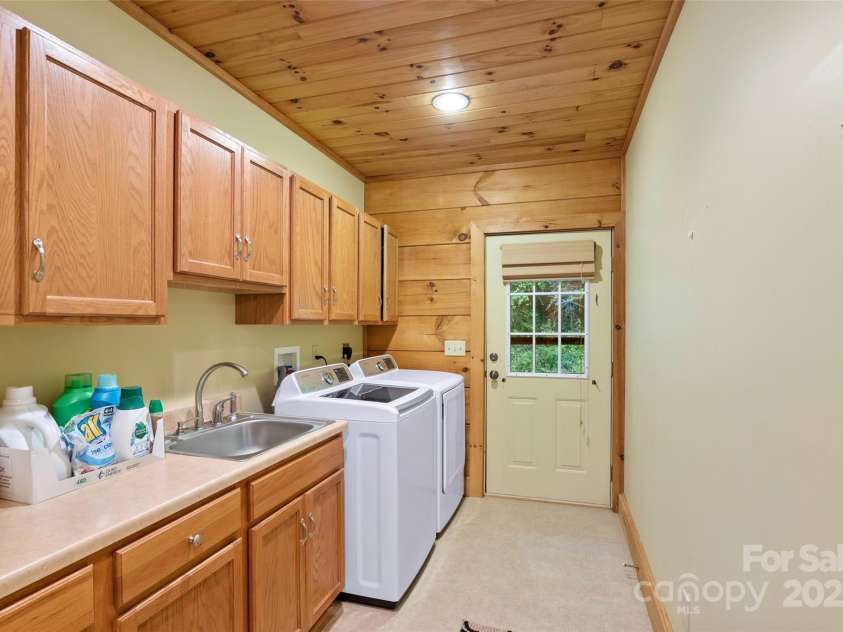 12215 Big Laurel Road, Marshall, NC 28753.  MLS# CAR4289922, YatesRealty ID 34872. Main level laundry room with extra cabinetry and sink, door leads to outside for easy access