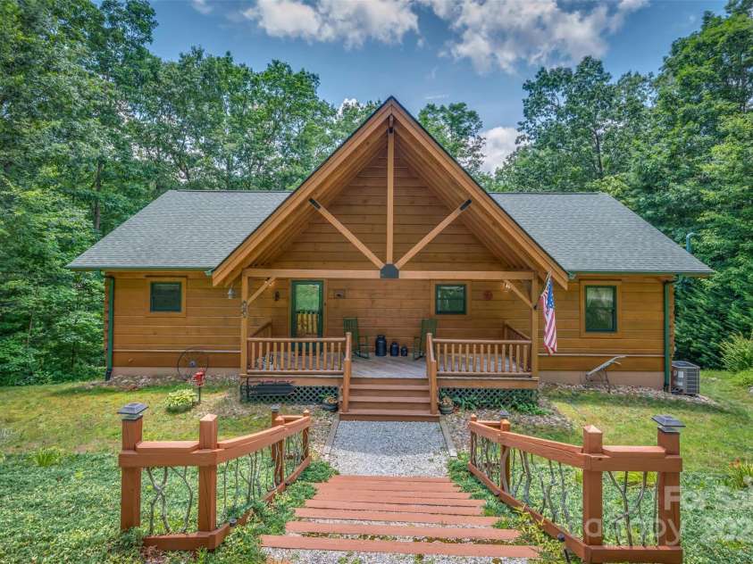 23 Jay Foster Way, Saluda, NC 28773.  MLS# CAR4278065, YatesRealty ID 35063. Custom Barna Log Home with notable entry staircase of Twig Railing and solar lighting. High pitched porch ceiling with exposed truss is one of many attributes!