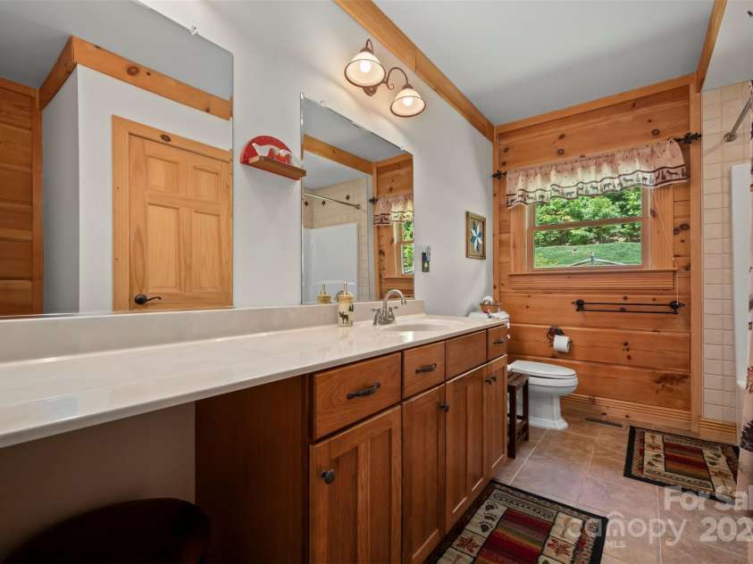 23 Jay Foster Way, Saluda, NC 28773.  MLS# CAR4323305, YatesRealty ID 35063. En-suite primary bath has ceramic tile floor, tub/shower combo w/tile border, make-up area