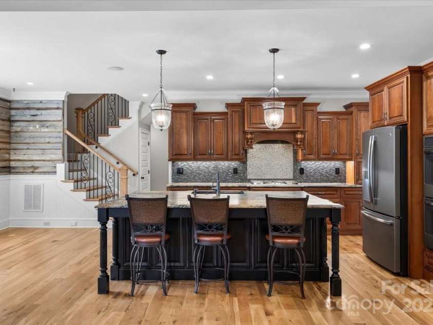 4038 Harmattan Drive, Denver, NC 28037.  MLS# CAR4297623, YatesRealty ID 35227. The cook's kitchen offers a gas range, wall oven too, warm wood tones and classic hanging lighting over the top of leathered/textured granite counters, stacked crown mouldings, under cabinter lighting, and so much more.
