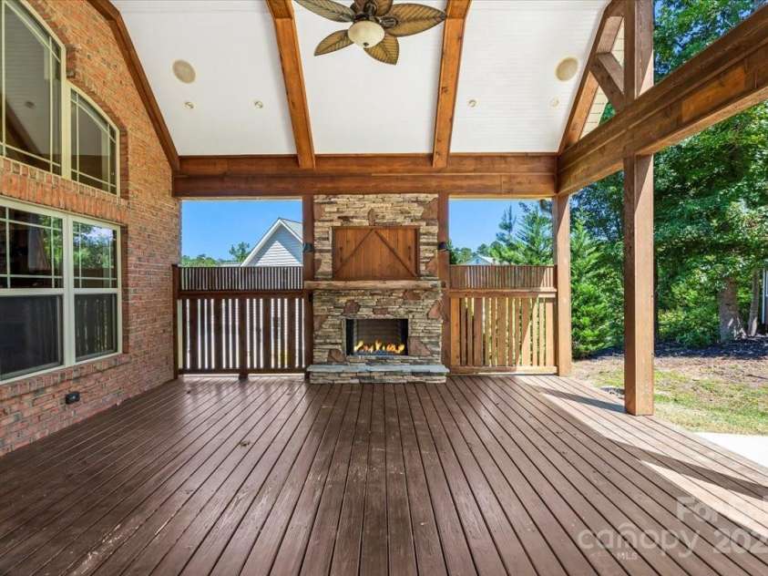 4038 Harmattan Drive, Denver, NC 28037.  MLS# CAR4297623, YatesRealty ID 35227. The covered back deck/porch has a gas log fireplace, celiing fan and just one step down to the flat back yard.. perfect for play or for adding a pool.  You can do it all here!