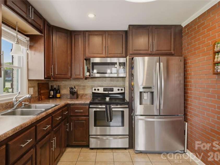 520 Eastway Avenue, Kannapolis, NC 28083.  MLS# CAR4396055, YatesRealty ID 35385. Remodeled kitchen featuring stainless steel appliances, a tile backsplash, and a brick accent wall