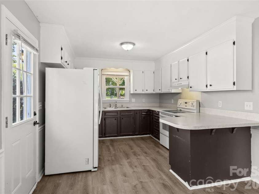 3571 Farm Lake Drive, Concord, NC 28027.  MLS# CAR4397456, YatesRealty ID 35526. Kitchen with white appliances, bar area for two bar stools and L-shaped kitchen