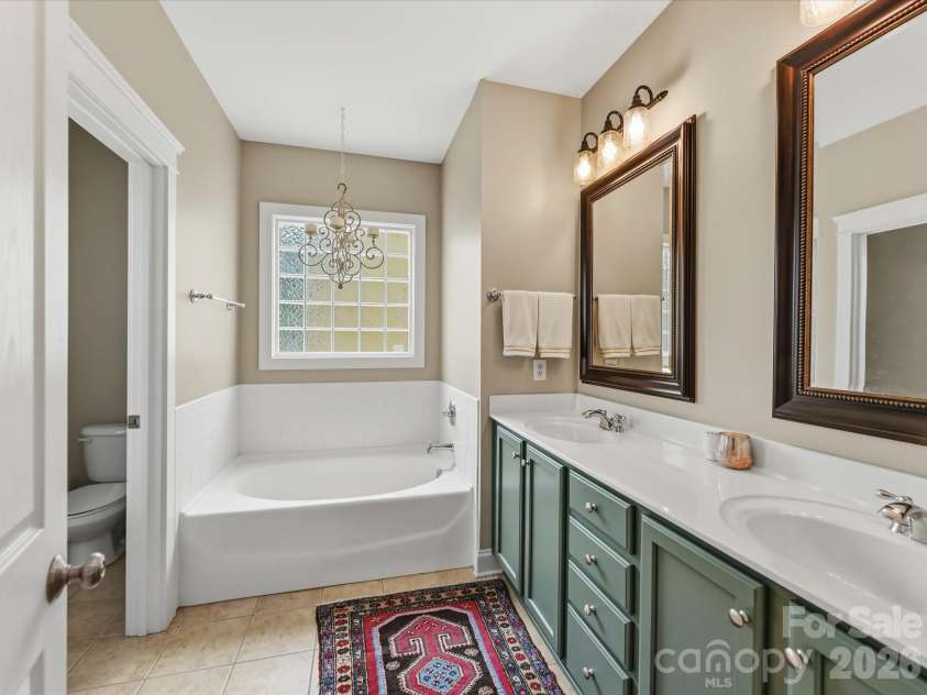 15715 Taviston Street, Huntersville, NC 28078.  MLS# CAR4401975, YatesRealty ID 36105. Unwind in the inviting primary bath complete with dual vanities and a soaking tub beneath a large picture window.