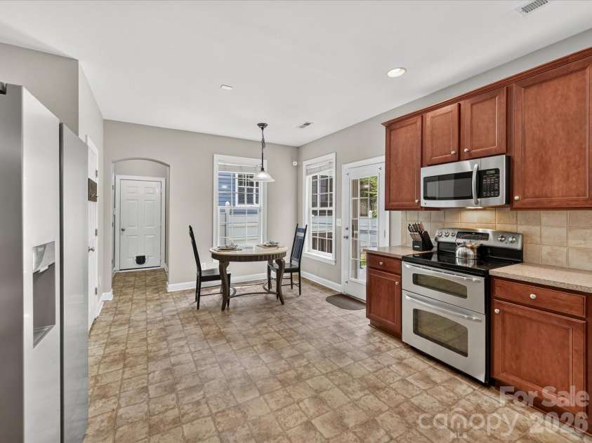 18625 The Commons Boulevard, Cornelius, NC 28031.  MLS# CAR4397710, YatesRealty ID 36310. The bright kitchen and adjoining breakfast nook offer the perfect setting for casual meals, featuring stainless steel appliances, abundant cabinetry, and direct access to the backyard for seamless indoor-outdoo