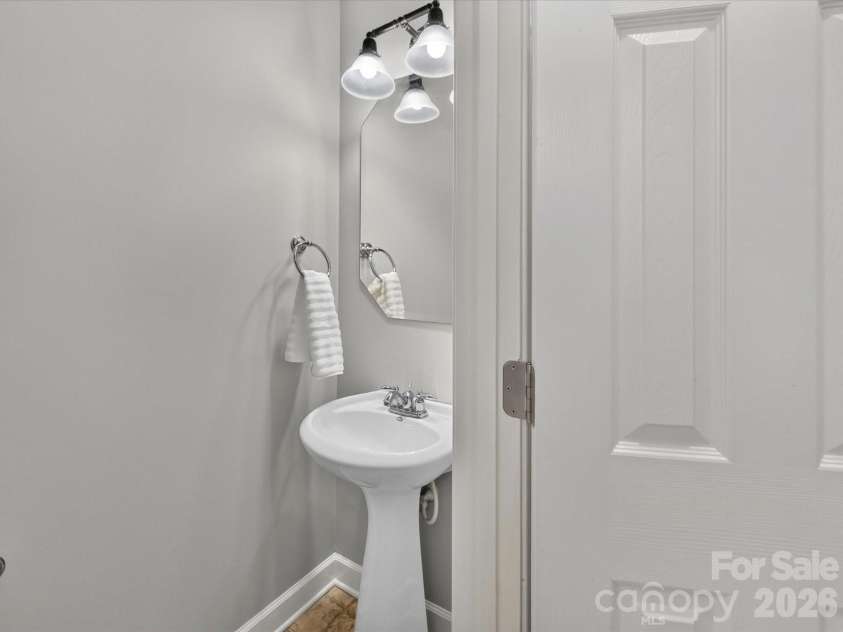 18625 The Commons Boulevard, Cornelius, NC 28031.  MLS# CAR4397710, YatesRealty ID 36310. The convenient main-level powder room is thoughtfully located for guests and features a pedestal sink with updated lighting.