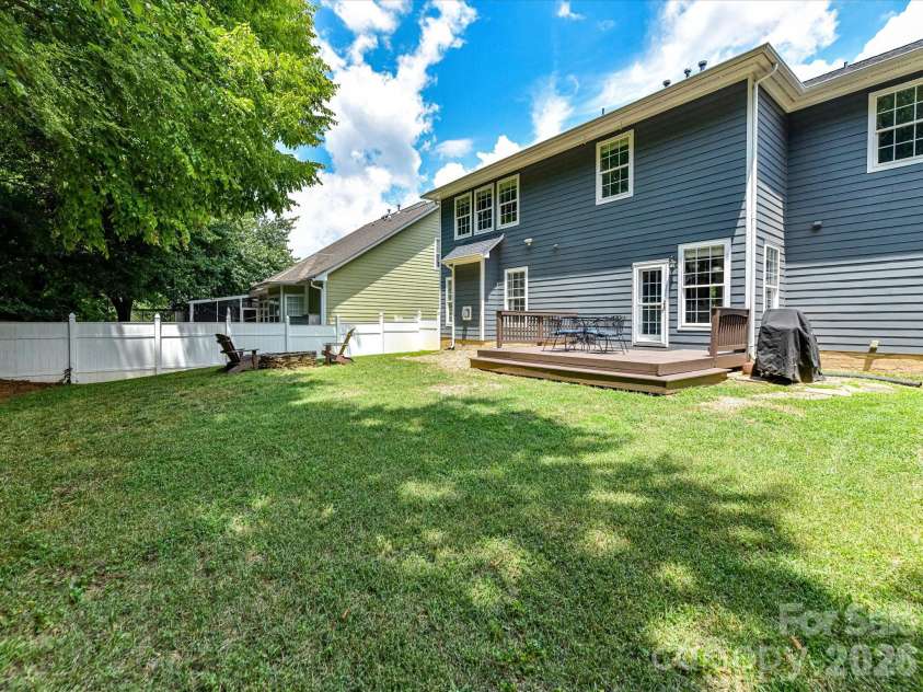 18625 The Commons Boulevard, Cornelius, NC 28031.  MLS# CAR4397710, YatesRealty ID 36310. The expansive, fully fenced backyard offers a level lawn, mature shade trees, a spacious deck, and a fire pit area, creating the perfect setting for outdoor entertaining and everyday enjoyment.