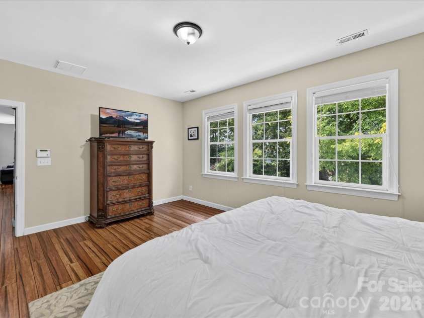 18625 The Commons Boulevard, Cornelius, NC 28031.  MLS# CAR4397710, YatesRealty ID 36310. The spacious primary suite on the upper level offers a peaceful retreat with abundant natural light, serene treetop views, and plenty of room for a sitting area or additional furnishings.