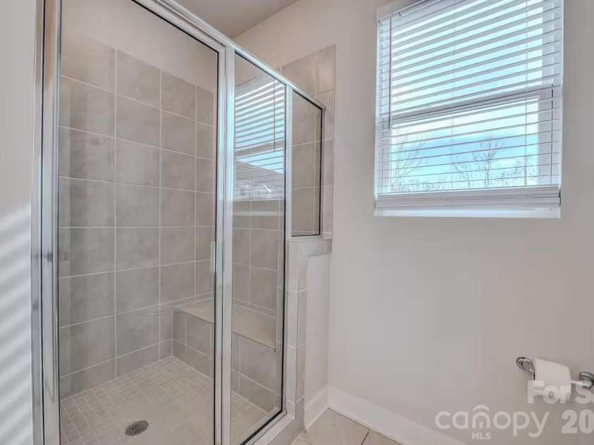 3023 Jolene Court, Charlotte, NC 28206.  MLS# CAR4399179, YatesRealty ID 36983. The bright and modern primary bathroom features a spacious vanity with ample counter space and a walk-in shower, offering both style and everyday functionality.