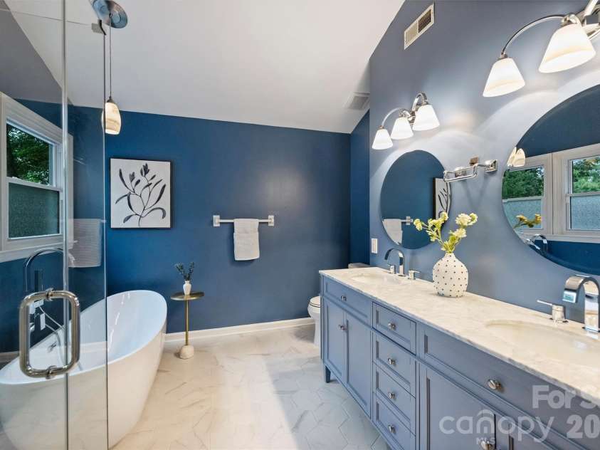 2500 Crescent Knoll Drive, Matthews, NC 28105.  MLS# CAR4399861, YatesRealty ID 37086. Beautifully renovated ensuite primary bath featuring a soaking tub, oversized walk-in glass shower, and dual vanity.
