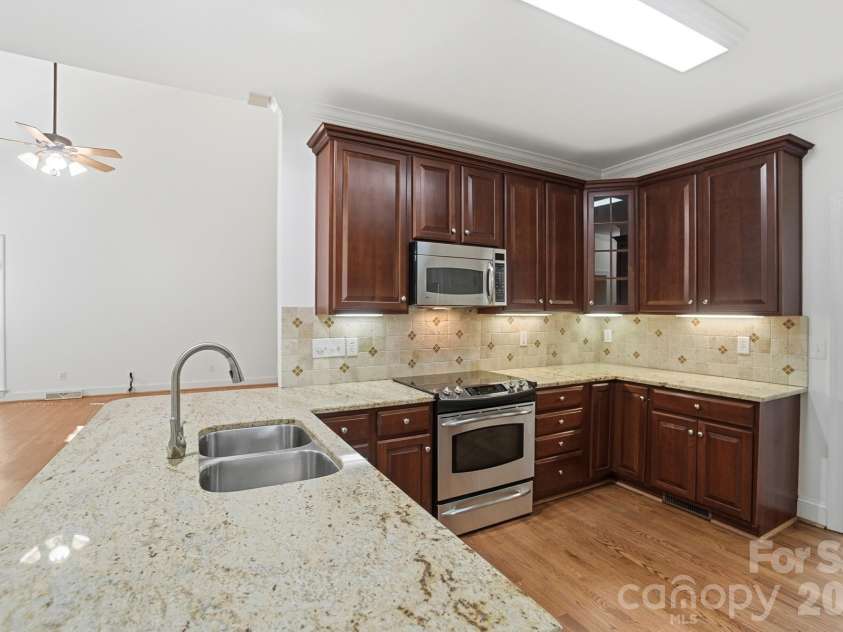 8044 Hawk Crest Court, Charlotte, NC 28270.  MLS# CAR4267919, YatesRealty ID 3752. Kitchen with granite counters/ bar seating area.  Under cabinet lighting, tile backsplash and 2 pantry spaces