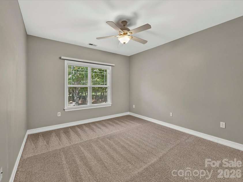 18814 Coachmans Trace, Cornelius, NC 28031.  MLS# CAR4399708, YatesRealty ID 37607. An oversized secondary bedroom offers flexible living space with a ceiling fan, closet space, and room for a variety of furniture layouts.