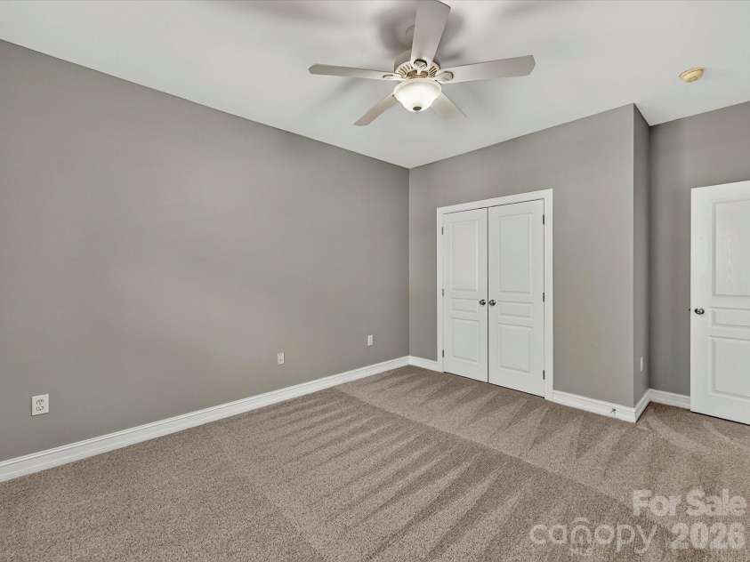 18814 Coachmans Trace, Cornelius, NC 28031.  MLS# CAR4399708, YatesRealty ID 37607. An oversized secondary bedroom offers flexible living space with a ceiling fan, closet space, and room for a variety of furniture layouts.