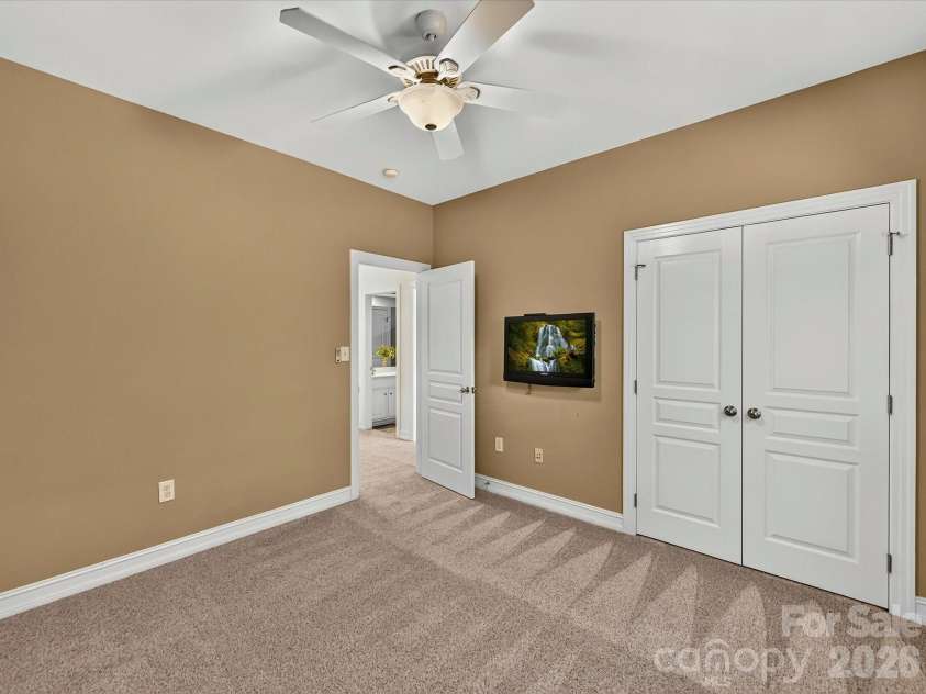18814 Coachmans Trace, Cornelius, NC 28031.  MLS# CAR4399708, YatesRealty ID 37607. Spacious secondary bedroom offers plush carpeting, a ceiling fan, generous closet space, and plenty of natural light.