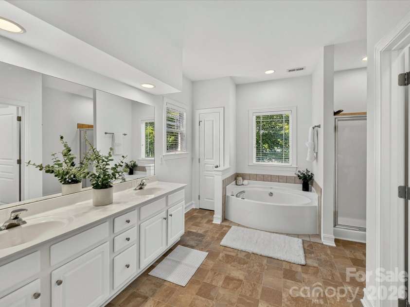 18814 Coachmans Trace, Cornelius, NC 28031.  MLS# CAR4399708, YatesRealty ID 37607. The luxurious primary bath features dual vanities, a relaxing garden tub, separate walk-in shower, and abundant natural light.