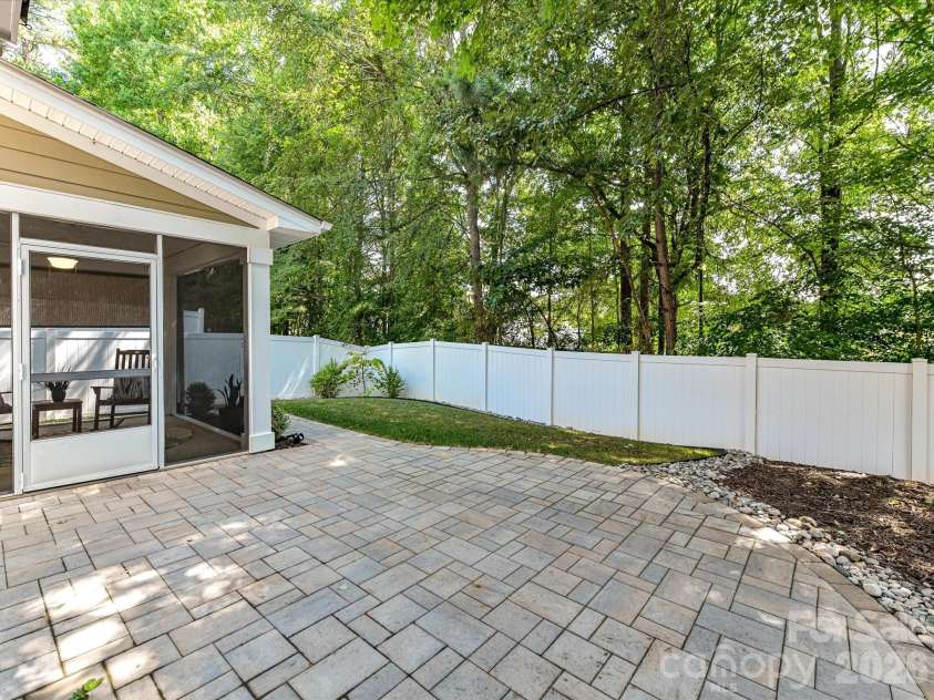 18814 Coachmans Trace, Cornelius, NC 28031.  MLS# CAR4399708, YatesRealty ID 37607. The private, fully fenced backyard is an outdoor oasis featuring a screened porch, expansive paver patio, and lush green space perfect for relaxing and entertaining.