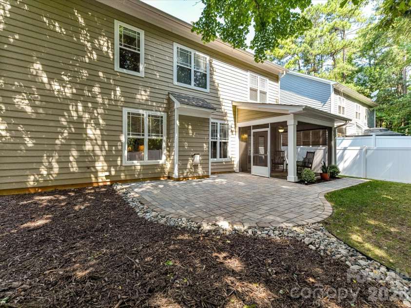 18814 Coachmans Trace, Cornelius, NC 28031.  MLS# CAR4399708, YatesRealty ID 37607. The private, fully fenced backyard is an outdoor oasis featuring a screened porch, expansive paver patio, and lush green space perfect for relaxing and entertaining.