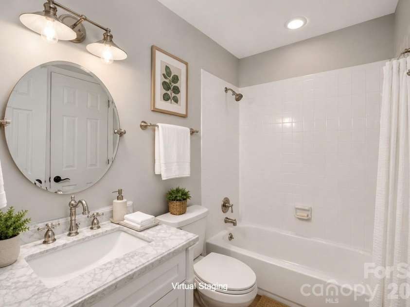 2520 Stradbrook Drive, Charlotte, NC 28210.  MLS# CAR4396722, YatesRealty ID 380. Second Bath: A round mirror and marble-topped vanity bring elegance to this full secondary bath, complete with a classic tub/shower combo. Crisp white tile keeps the space feeling clean and bright.