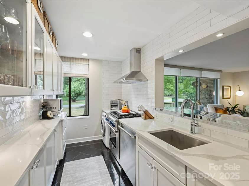1300 Queens Road, Charlotte, NC 28207.  MLS# CAR4283635, YatesRealty ID 3800. Kitchen with Custom Cabinets, Subway Tile Backsplash, Undercounter Lighting, Quartz Counters, Black Marble Floor, Washer/Dryer, Remote Shade