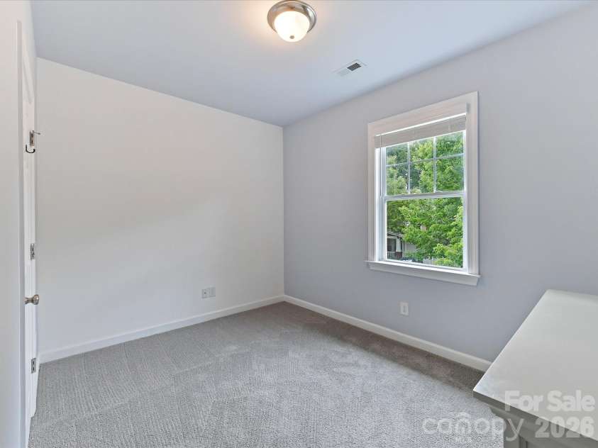 8707 Lake Pines Drive, Cornelius, NC 28031.  MLS# CAR4402781, YatesRealty ID 38115. Bright secondary bedroom offers plush carpeting, a large window for natural light, and flexible space ideal for family, guests, or a home office.