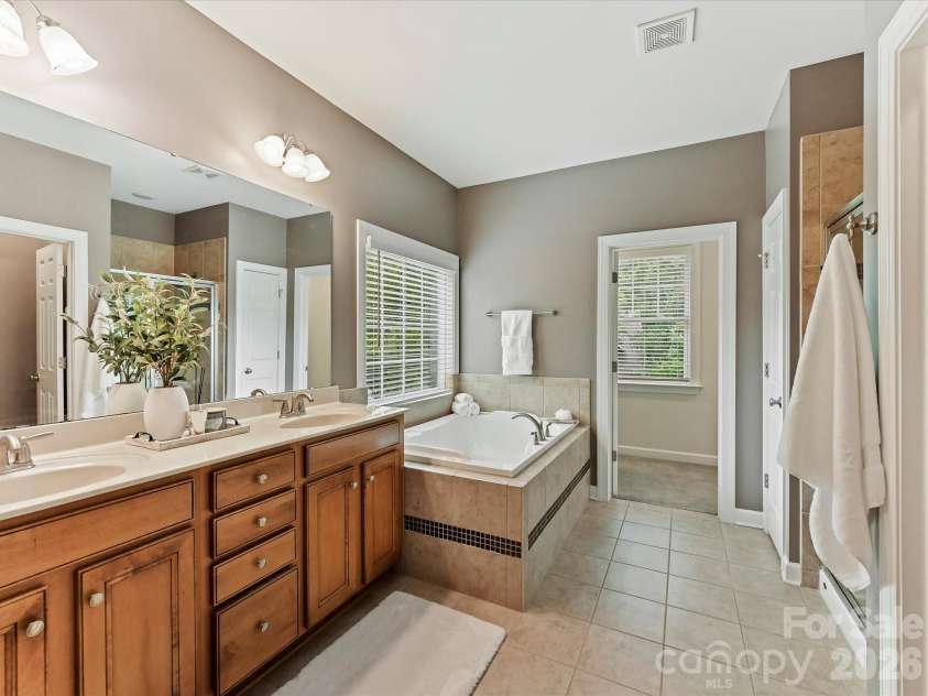 8707 Lake Pines Drive, Cornelius, NC 28031.  MLS# CAR4402781, YatesRealty ID 38115. Luxurious primary bath features dual vanities, a relaxing soaking tub, a separate tiled shower, and abundant natural light for a spa-like retreat.