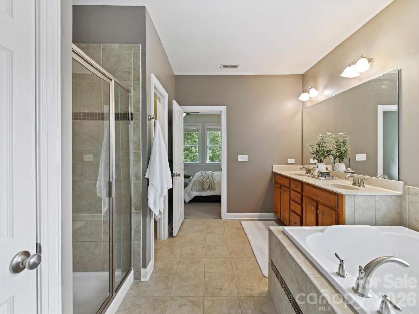 8707 Lake Pines Drive, Cornelius, NC 28031.  MLS# CAR4402781, YatesRealty ID 38115. Luxurious primary bath features dual vanities, a relaxing soaking tub, a separate tiled shower, and abundant natural light for a spa-like retreat.