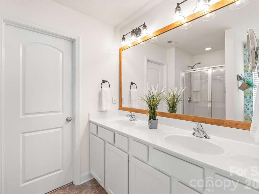 4303 Hampstead Heath Drive, Waxhaw, NC 28173.  MLS# CAR4402437, YatesRealty ID 38129. The primary ensuite is a spa-like oasis, featuring double sinks, elegant designer lighting, and a beautifully framed mirror that adds a polished, custom touch.