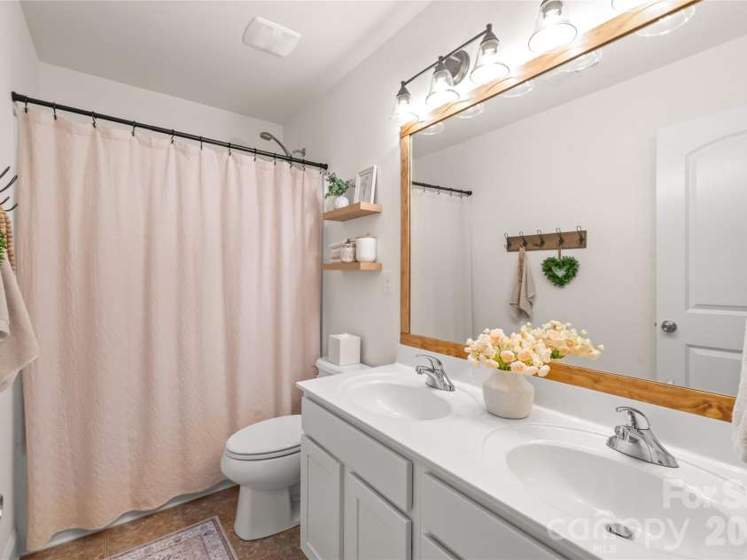 4303 Hampstead Heath Drive, Waxhaw, NC 28173.  MLS# CAR4402437, YatesRealty ID 38129. The second-floor full bathroom is highly functional with double sinks, elegant designer lighting, and a framed mirror, plus a classic tub/shower combination.
